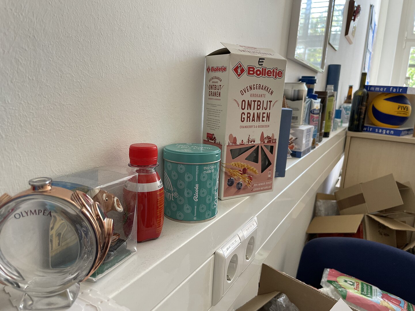 Verschiedene Verpackungen aus unterschiedlichen Materialien und Formen stehen aufgereiht an der Wand.