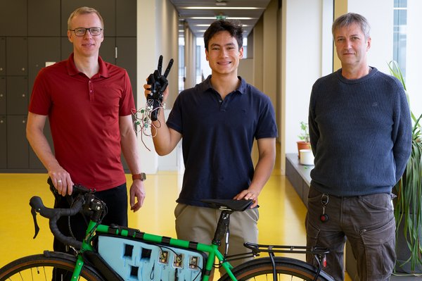 Gruppenfoto, Martin Meister hat in der rechten Hand einen Handschuh und vor ihm steht ein Fahrrad aus dem Bikelab mit Messtechnik