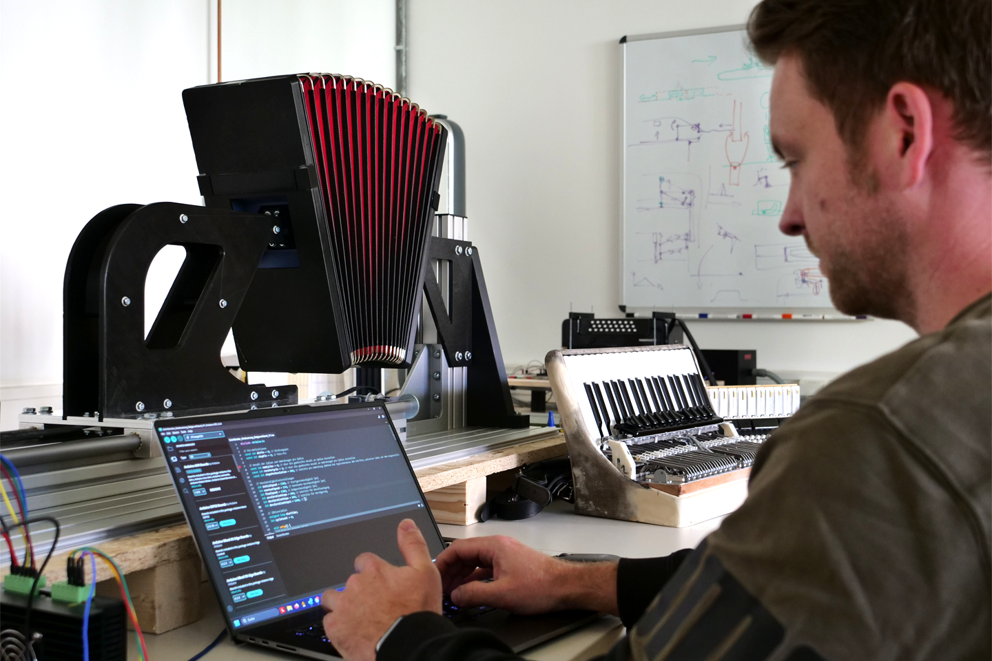 Mitarbeiter am Laptop im Hintergrund Akkordeons/bei Verlinkung führt Link zur Projektwebsite