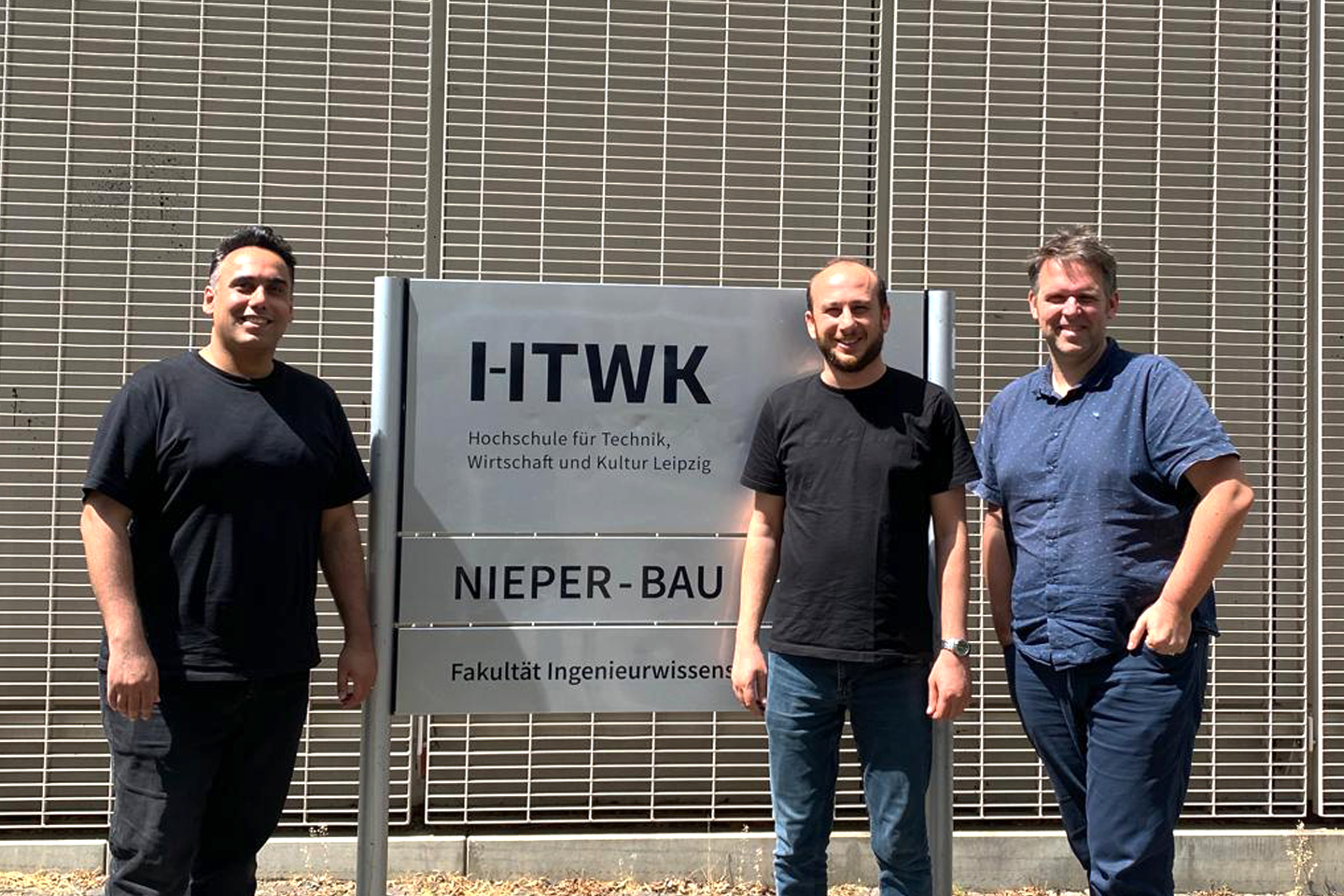 Portraitaufnahme von Prof. Ferhat Şen (Mitte) mit Davood Peyrow Hedayati (links) und Prof. Robert Böhm (rechts) vor dem Nieper-Bau der HTWK Leipzig